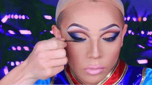 A Drag Queen Is Applying Makeup To Her Eyes GIF