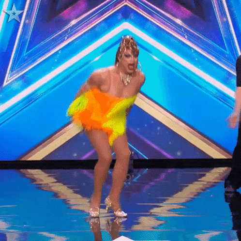 a drag queen is dancing on a stage with a blue background
