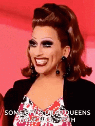 a drag queen is smiling and wearing earrings .