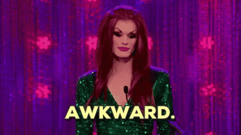 A Drag Queen Is Standing In Front Of A Microphone With The Word Awkward Written On It . GIF
