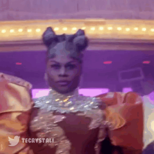 Drag Queen Standing In Front Of Purple Wall And Twitter Logo GIF