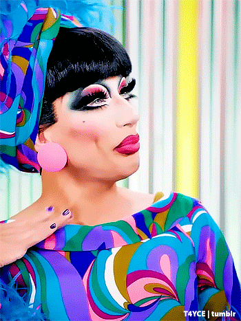 a drag queen is wearing a colorful dress and a headband