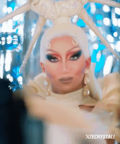 Drag Queen In White Costume With Spider Headpiece GIF