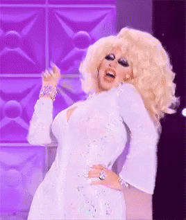 a drag queen is wearing a white dress and dancing on a stage .