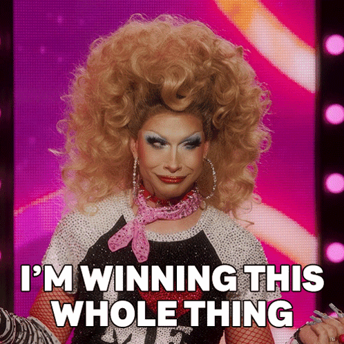 A Drag Queen Says " I 'M Winning This Whole Thing " On A Pink Background GIF