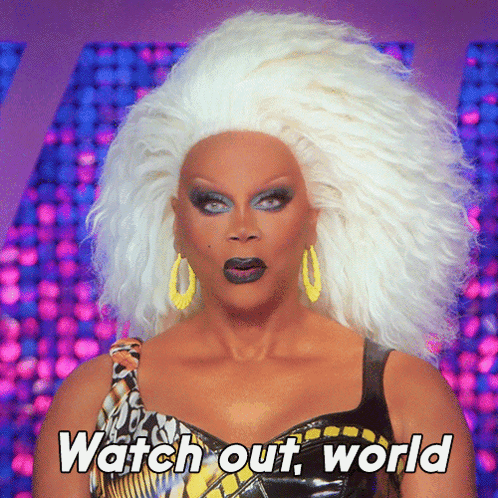 A Drag Queen Says " Watch Out World " While Wearing A Wig GIF