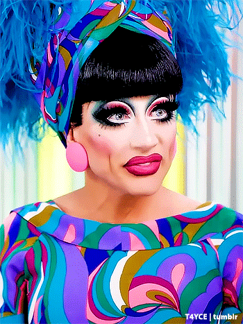 a drag queen wearing a colorful dress and feathered headpiece