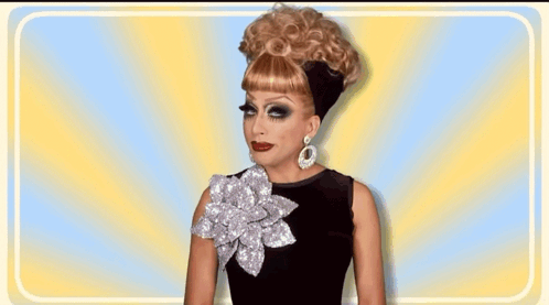 a drag queen wearing a wig and earrings is smiling