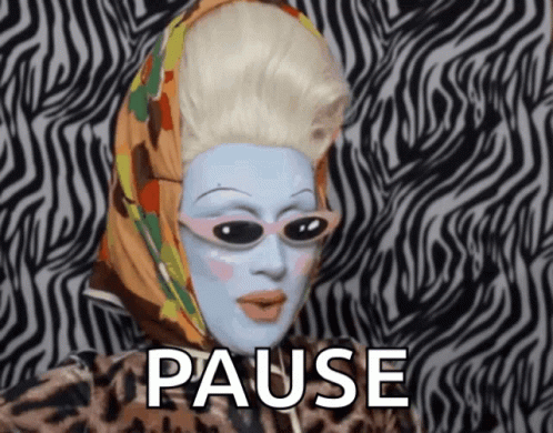 A Drag Queen With A Scarf Around Her Head And The Word Pause Behind Her GIF