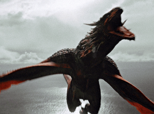 A Dragon Is Flying Over A Body Of Water GIF