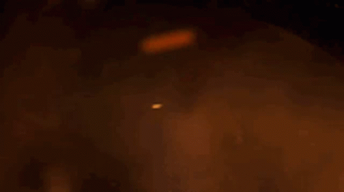 A Dragon Is Flying Through The Air In Front Of A Fire . GIF