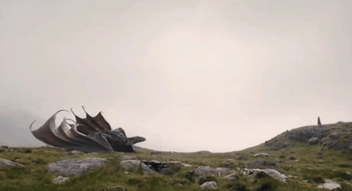 a dragon is sitting on top of a hill with its wings spread