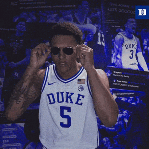 A Duke Basketball Player Adjusts His Sunglasses While Wearing A Blue And White Jersey GIF