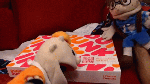A Dunkin Donuts Box Sits On A Couch Next To Stuffed Animals GIF
