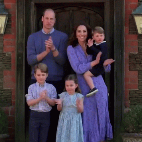 A Family Is Posing For A Picture In Front Of A Door While Clapping . GIF