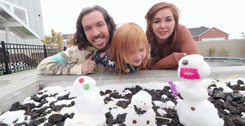 A Family Is Posing For A Picture In Front Of A Pile Of Snowmen GIF