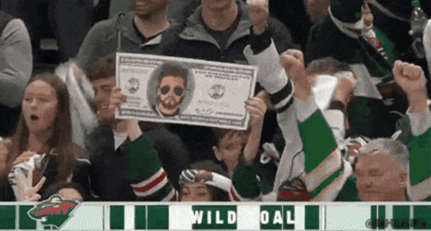 A Fan Holds Up A Dollar Bill With A Picture Of A Man On It In Front Of A Sign That Says Wild Goal GIF