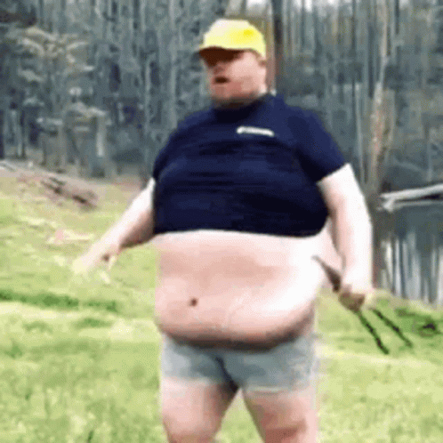 A Fat Man In A Blue Shirt And Shorts Is Standing In The Grass . GIF