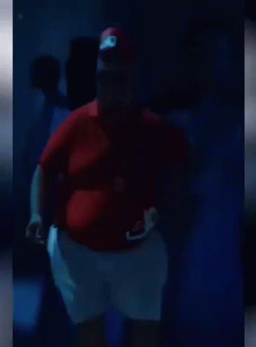 A Fat Man Is Dancing In A Dark Room . GIF