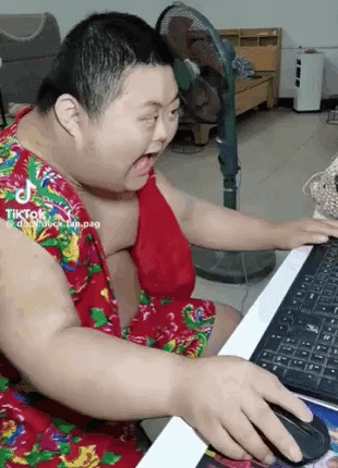 A Fat Man Is Sitting At A Desk Using A Computer . GIF