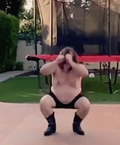 A Fat Man Is Squatting Down In Front Of A Trampoline . GIF
