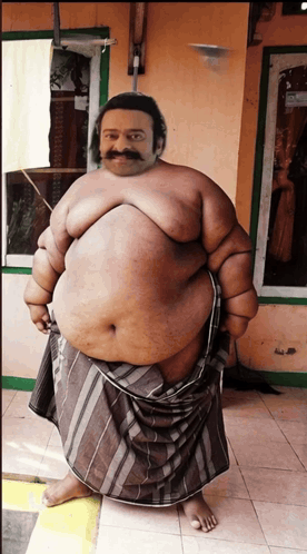 A Fat Man With A Mustache Is Standing In Front Of A Building GIF