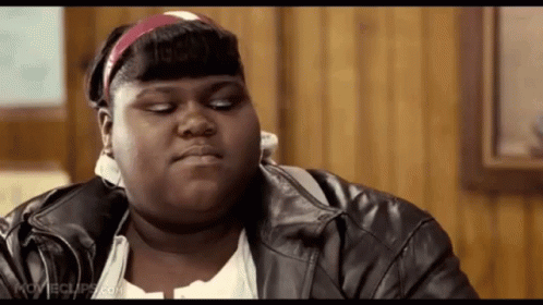 A Fat Woman Wearing A Leather Jacket And A Headband Is Sitting At A Table . GIF