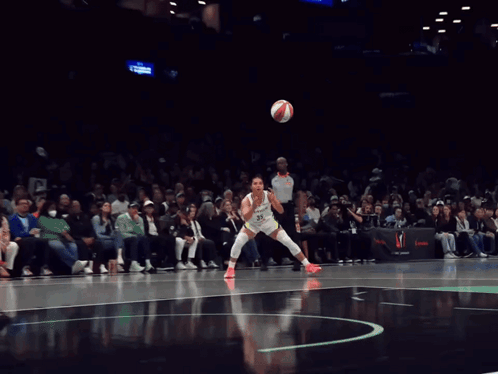 A Female Basketball Player Dribbles A Ball In Front Of A Crowd That Is Watching A Game GIF