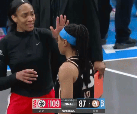 a female basketball player high fives another female basketball player during a game