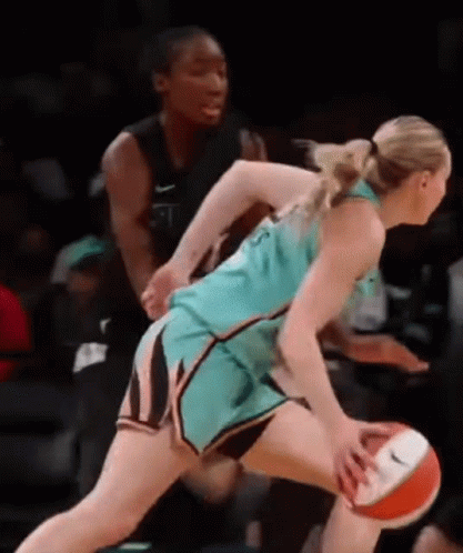 A Female Basketball Player Is Dribbling The Ball While Another Female Basketball Player Tries To Stop Her . GIF