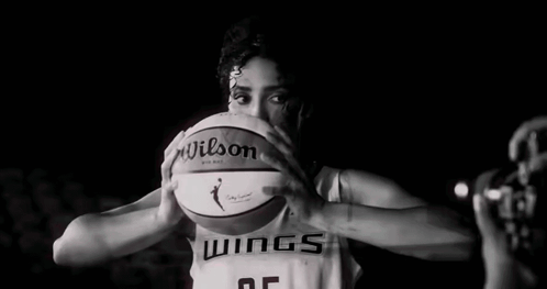 A Female Basketball Player Is Holding A Basketball In Front Of Her Face In A Black And White Photo . GIF