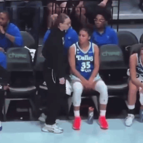 A Female Basketball Player Wearing A Dallas Jersey Sits In The Stands GIF