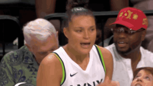 A Female Basketball Player Wearing A Nike Jersey Is Talking To A Man In A Red Hat GIF