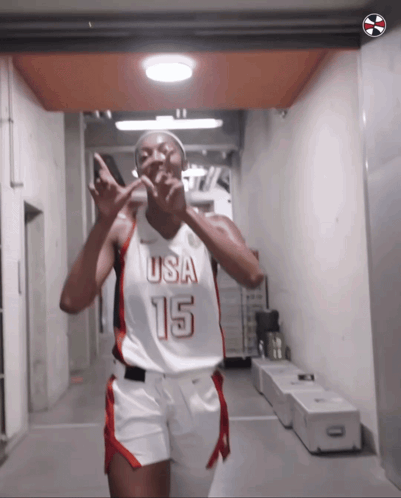 a female basketball player wearing a usa 15 jersey is giving a peace sign