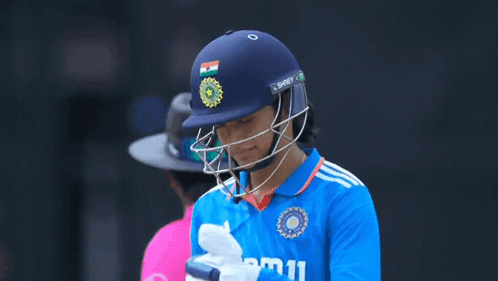 A Female Cricket Player Wearing A Helmet And Gloves Is Looking At Her Phone GIF