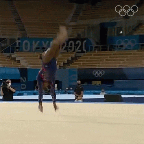 A Female Gymnast Is Doing A Handstand On The Floor In A Gym . GIF