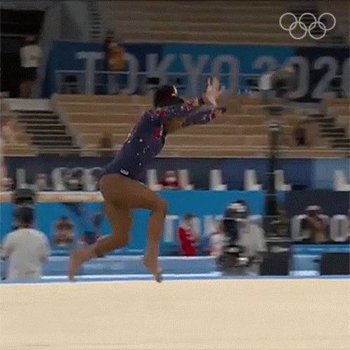 A Female Gymnast Is Doing A Trick On The Floor In Front Of A Crowd At The Olympics . GIF