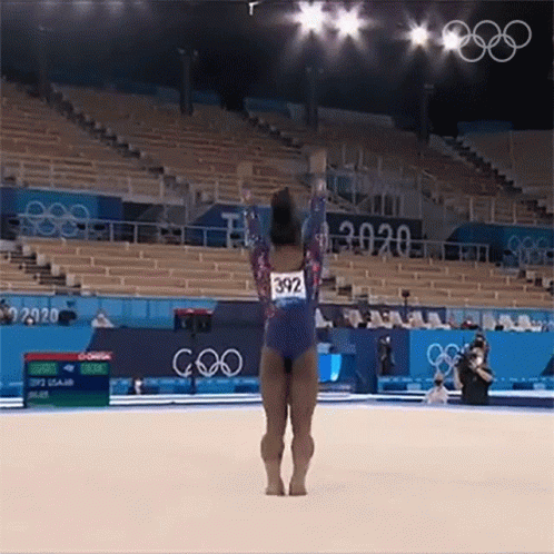 A Female Gymnast Is Doing A Trick On The Floor While Wearing A Number 392 Leotard . GIF