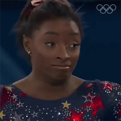 A Female Gymnast Is Making A Funny Face While Wearing A Blue Dress With Stars And A Red Bow In Her Hair . GIF