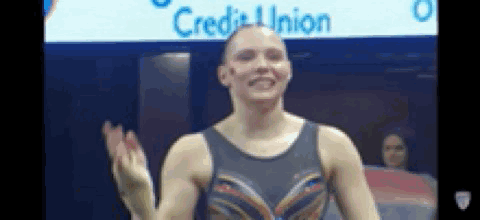 a female gymnast is waving her hand in front of a sign that says credit union