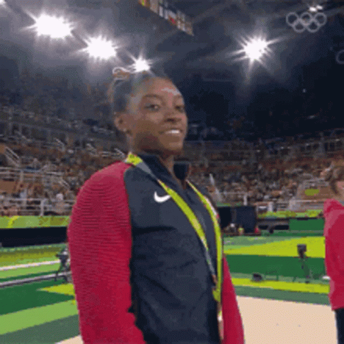 A Female Gymnast Wearing A Nike Jacket And A Medal Around Her Neck GIF