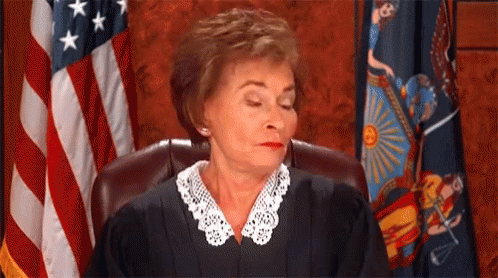 A Female Judge Is Sitting In Front Of An American Flag In A Courtroom . GIF