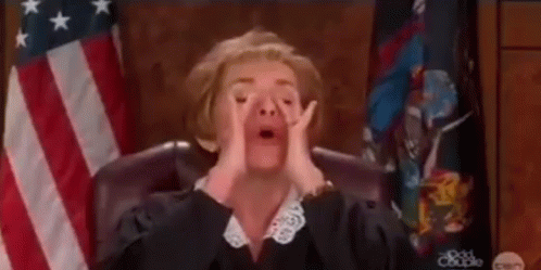 A Female Judge Is Sitting In Front Of An American Flag In A Courtroom . GIF