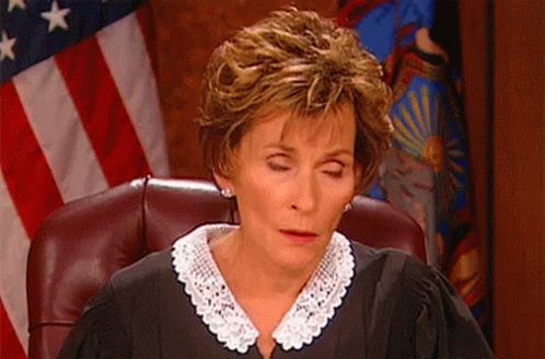 A Female Judge Sitting In Front Of An American Flag GIF