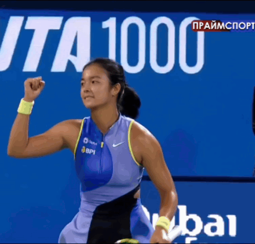 A Female Tennis Player Holds Her Fist In The Air In Front Of A Sign That Says " Ita 1000 " GIF
