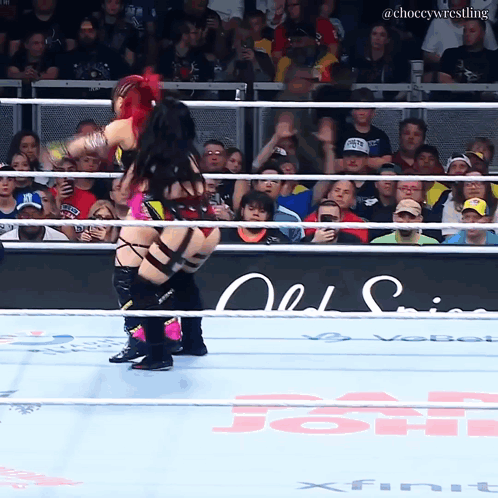 A Female Wrestler Is Being Lifted In The Air By Another Wrestler In A Wrestling Ring GIF