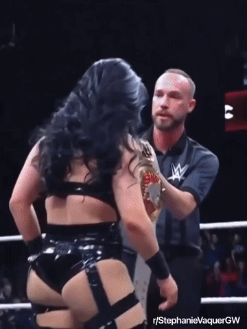 A Female Wrestler Is Holding A Wrestling Championship Belt While Standing Next To A Referee GIF