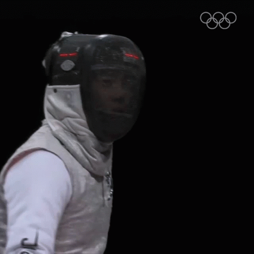 A Fencer Is Wearing A Helmet And Holding A Sword GIF