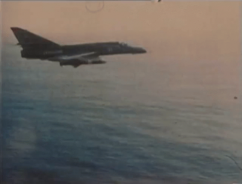 A Fighter Jet Is Flying Over A Body Of Water With The Number 21 On The Side GIF
