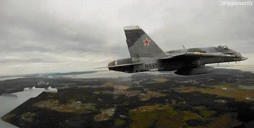 A Fighter Jet Is Flying Over A Landscape With A Large Star On The Tail . GIF